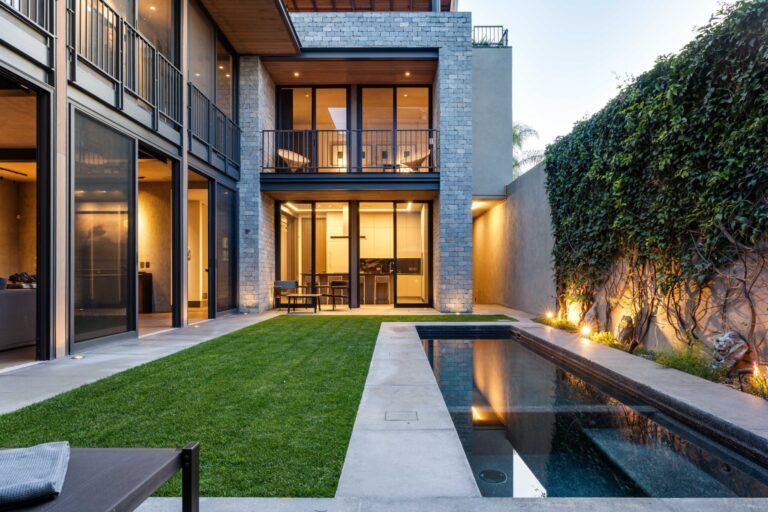 Modern two-story house courtyard with large glass walls, stone facade, and warm interior lighting seen through doors and windows.] , but try to be coherent; I’ll provide clean options.
