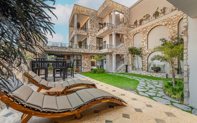 Stone luxury home courtyard with sun loungers, a lawn and stepping stones, San Miguel de Allende