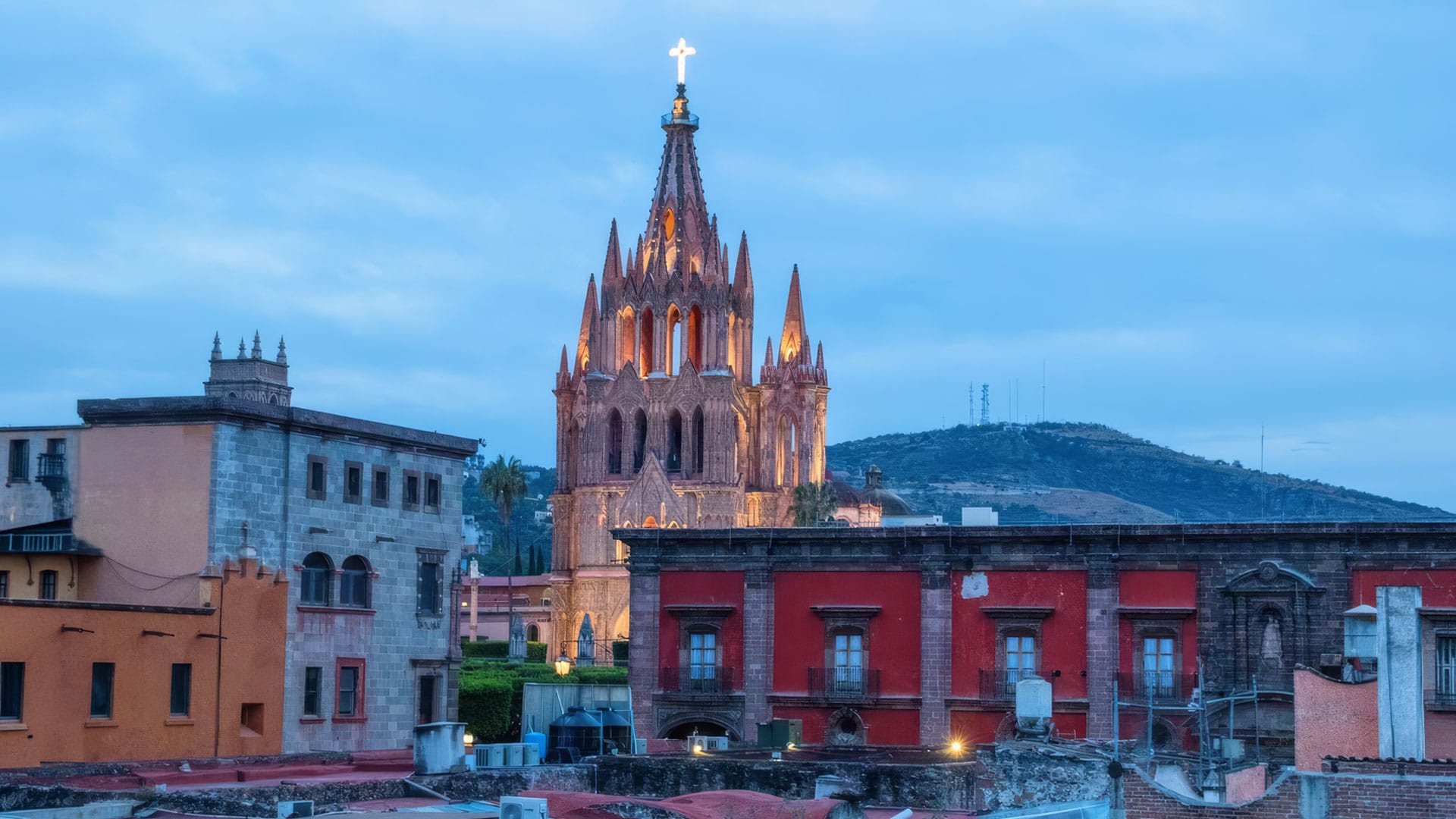 Gothic church spire rising above colorful city buildings at dusk.