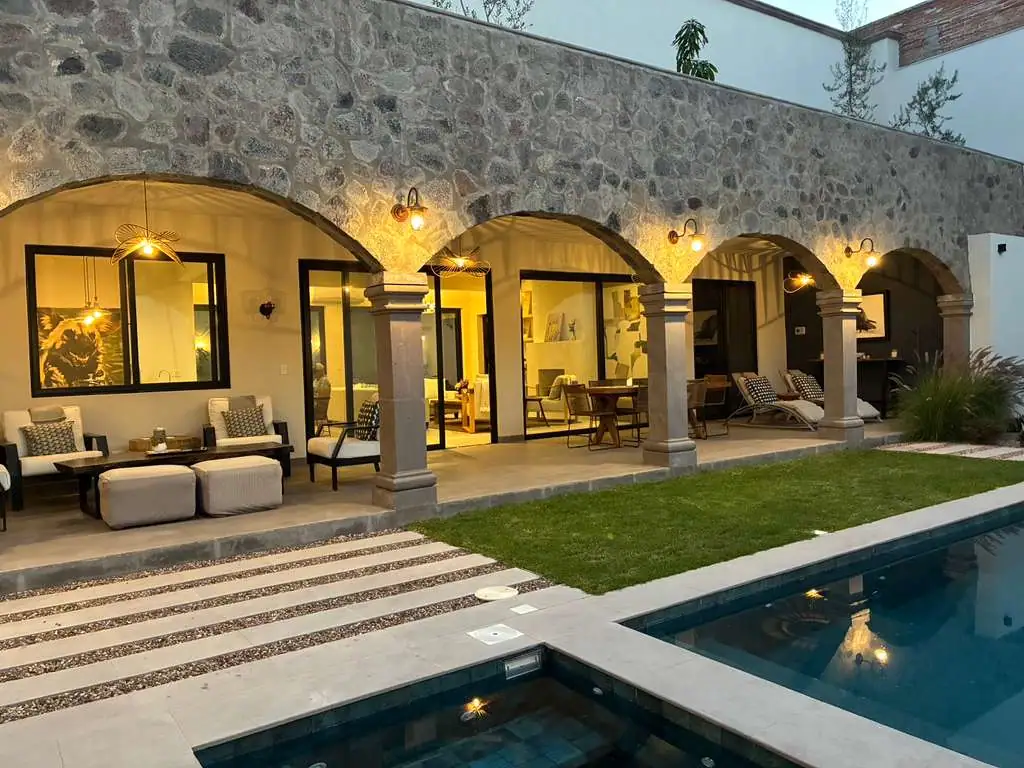 Stone-arched patio with outdoor seating overlooking a rectangular pool at dusk; warm lights illuminate lounge chairs and glass doors, San Miguel de Allende