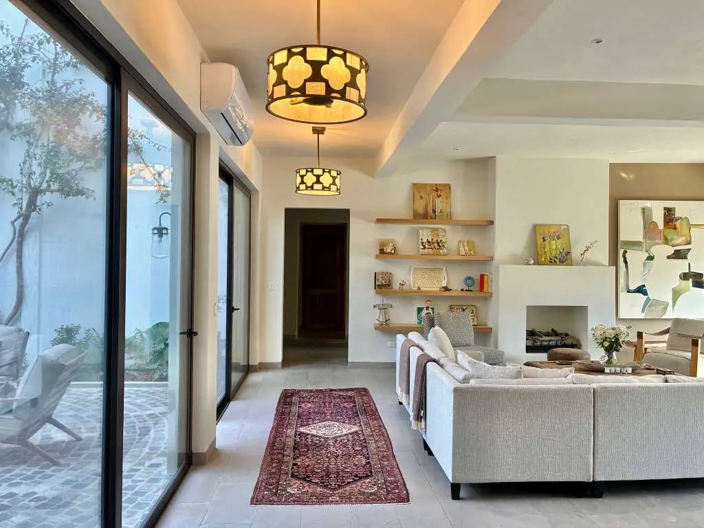 Bright modern living room with a beige sectional, glass doors to a patio, and a patterned rug, San Miguel de Allende