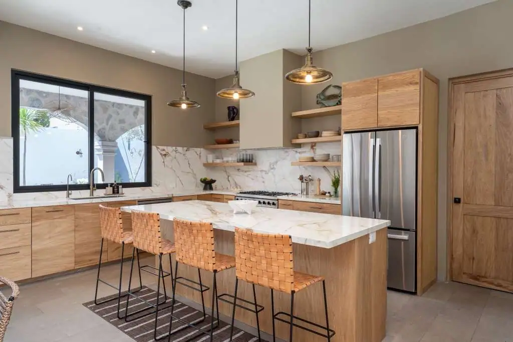 Modern kitchen with marble island, wooden cabinets, open shelves, and a stainless steel refrigerator, San Miguel de Allende