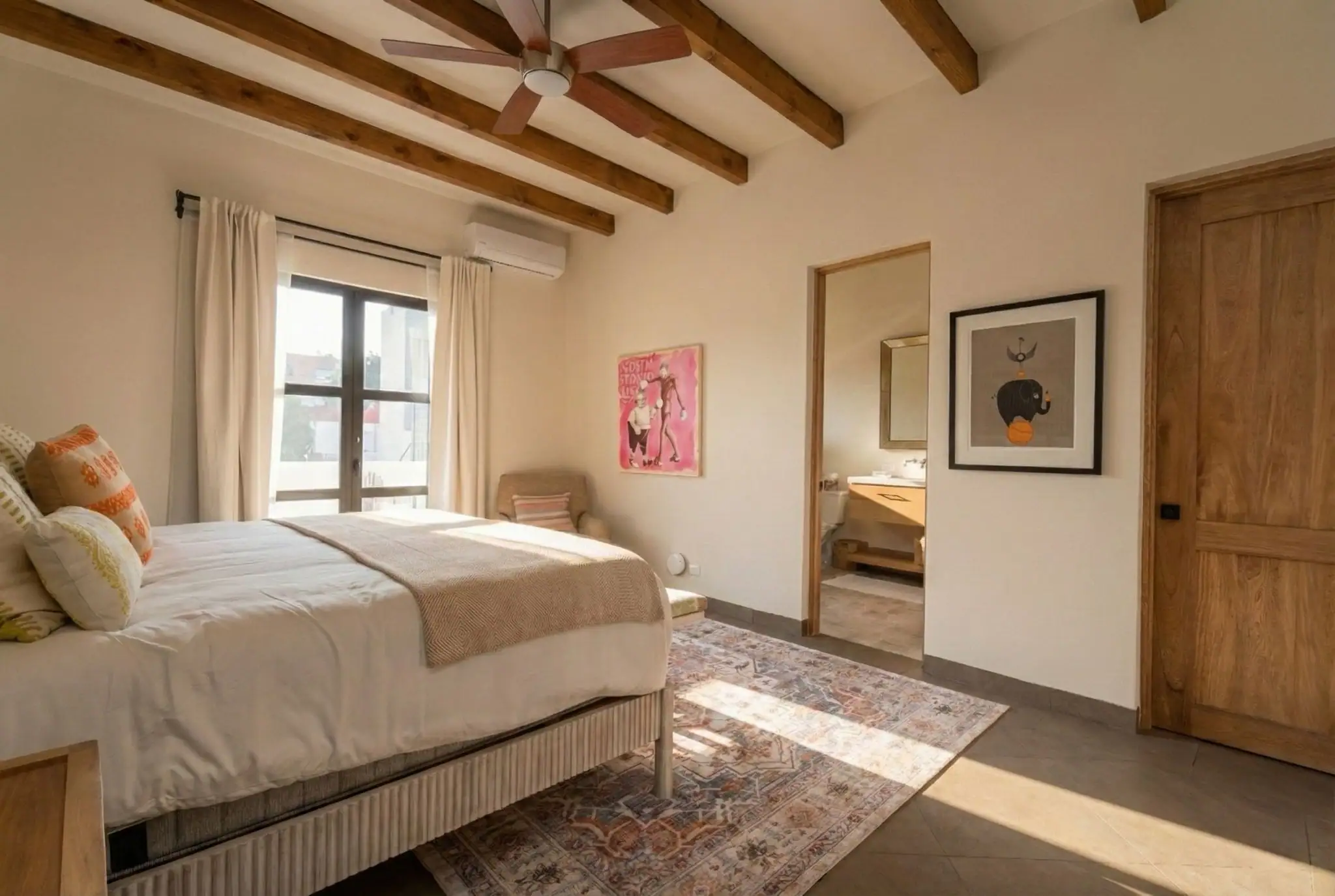 Bedroom with beige bedding, exposed wooden ceiling beams, and a ceiling fan in warm light, San Miguel de Allende