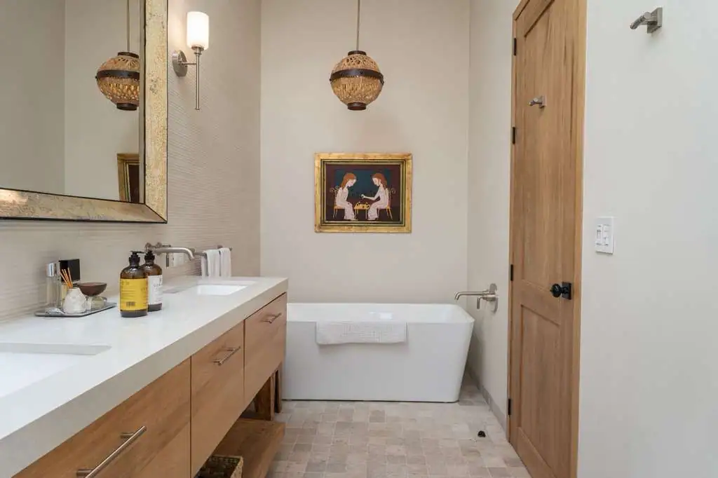 Modern bathroom with a long white countertop, double sinks, and wooden cabinets beside a freestanding tub, San Miguel de Allende