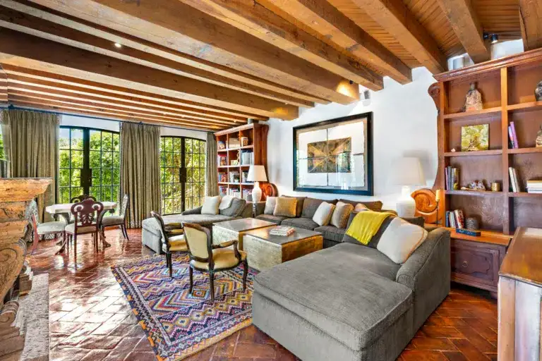 Cozy living room with exposed wooden beam ceiling, large grid windows, and a gray sectional sofa, San Miguel de Allende