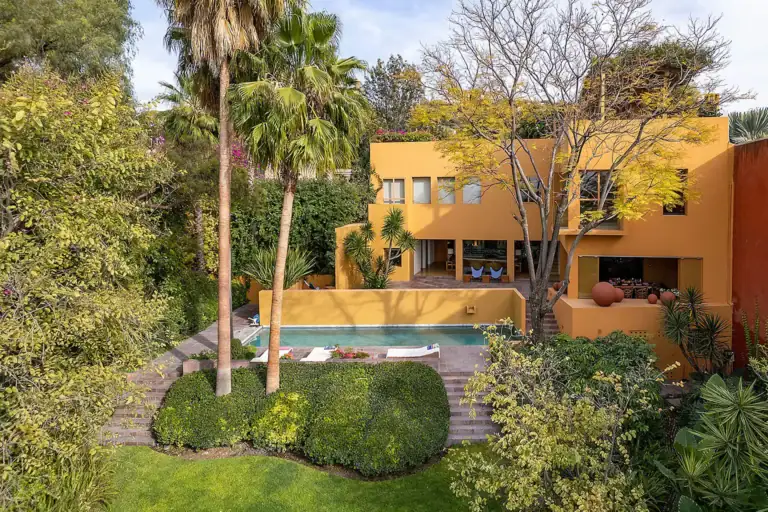 Casa Legorreta, orange modernist house with a rectangular pool, stone terraces, tall palm trees and lush gardens, San Miguel de Allende