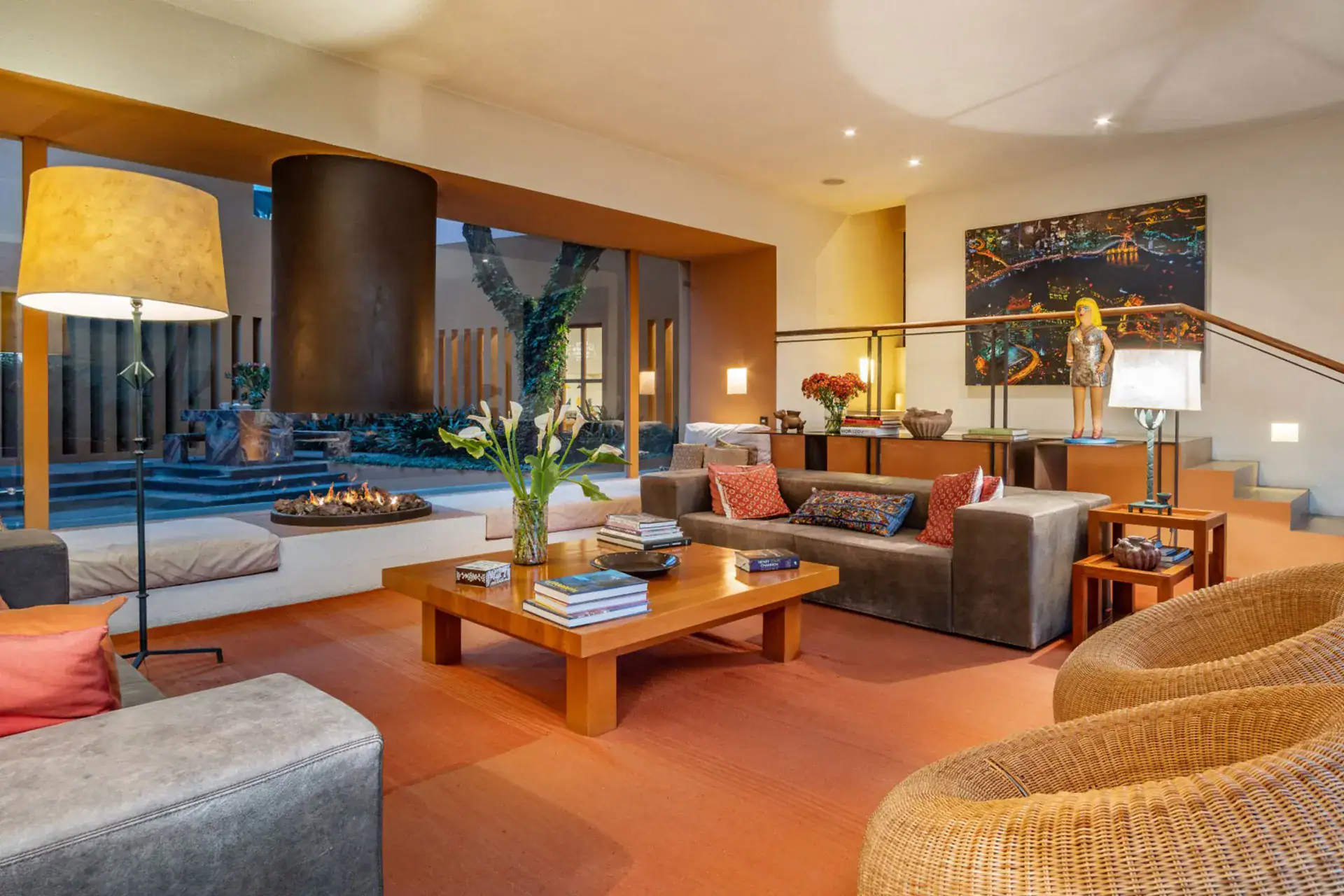 Luxurious living room with a fireplace, orange carpet, and a large oak coffee table surrounded by sectional sofas and colorful cushions, San Miguel de Allende
