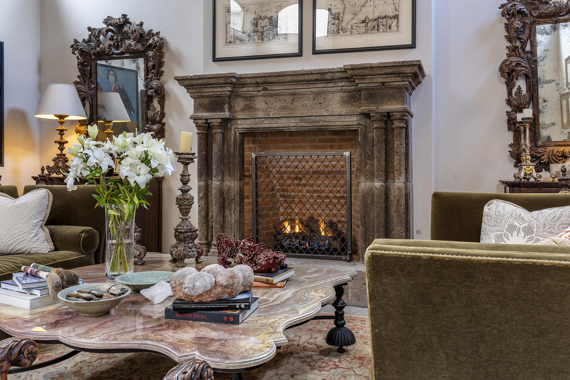 Cozy living room with a carved stone fireplace, marble coffee table, and a bouquet of white lilies in a glass vase, San Miguel de Allende