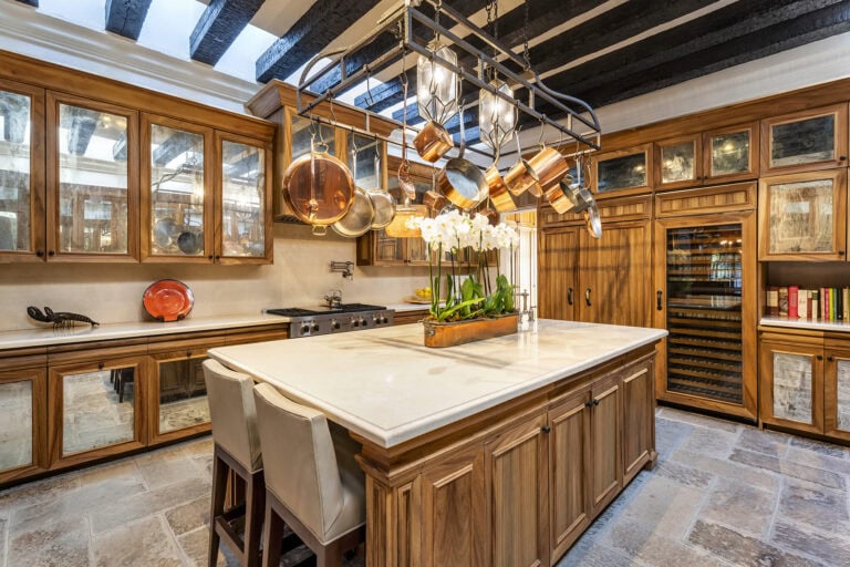Rustic kitchen with a marble island, wooden cabinetry, and a ceiling pot rack holding copper pots and pans above the counter, San Miguel de Allende
