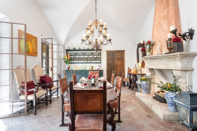 Elegant dining room with a long wooden table set for dinner under a wrought-iron chandelier, San Miguel de Allende