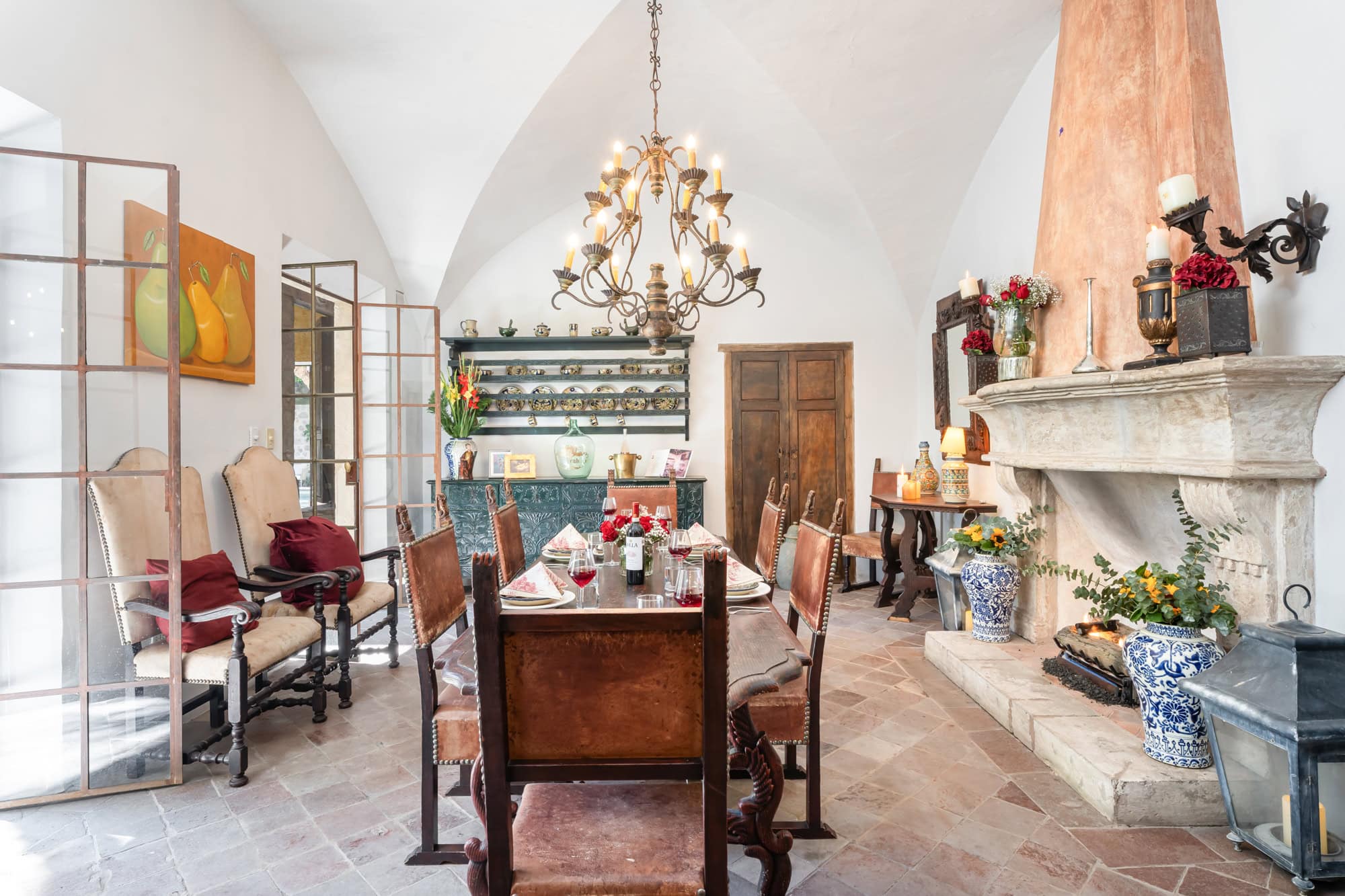 Elegant dining room with a long wooden table set for dinner under a wrought-iron chandelier, San Miguel de Allende