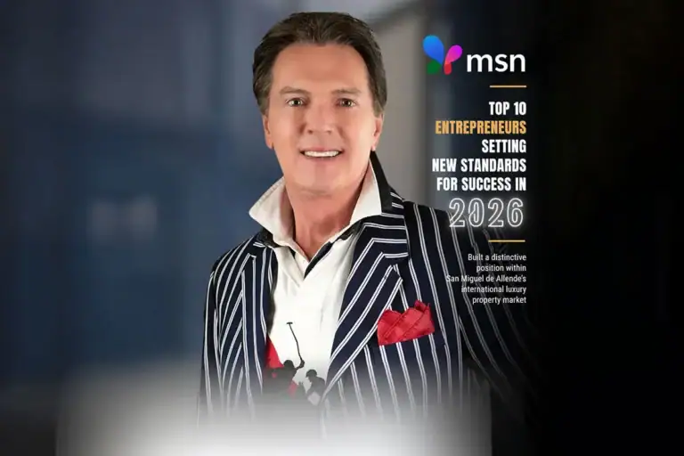 Smiling man in a navy pinstripe suit with a red pocket square beside a magazine cover reading 'Top 10 Entrepreneurs... 2026' (MSN).