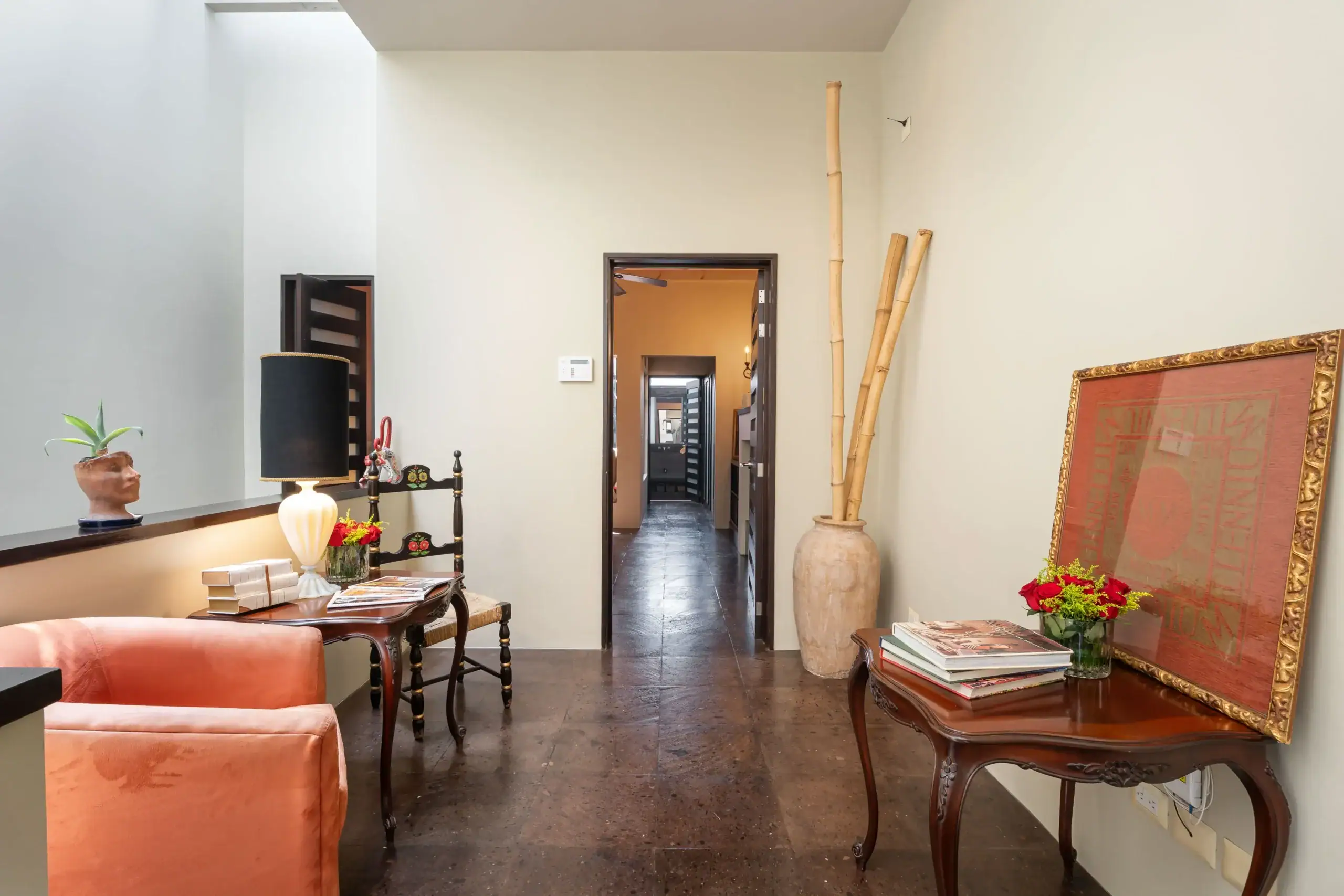 Cozy living room corner with an orange sofa, wooden coffee table, lamps, and a large framed red artwork propped against the wall on the right, San Miguel de Allende