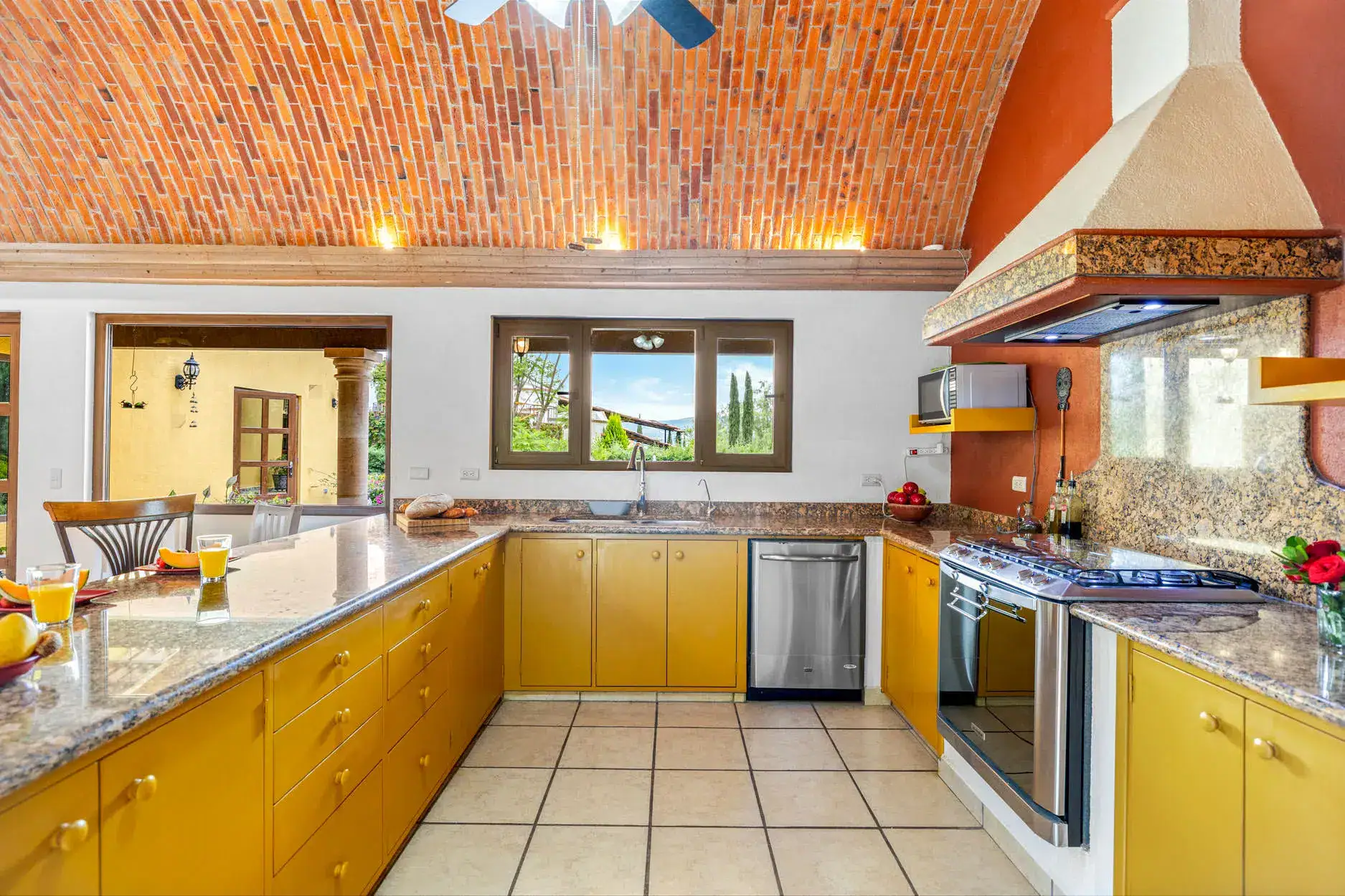 Bright kitchen featuring yellow cabinets, granite countertops, and a brick vaulted ceiling with warm lighting, San Miguel de Allende