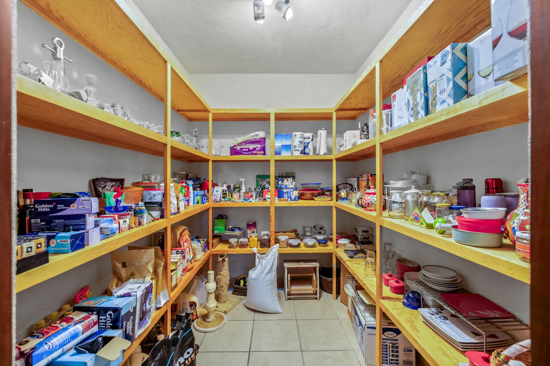 Pantry cluttered with wooden shelves filled with glassware, dishes, boxes, and containers, San Miguel de Allende