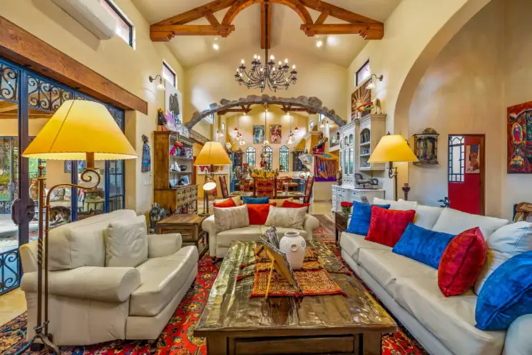 Spacious living room with white sectional sofas, colorful cushions, rustic wood beams, and chandelier, San Miguel de Allende