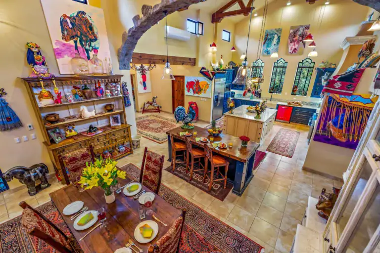 Colorful eclectic dining room with art-filled walls, pottery on shelves, and a table set for a meal with yellow napkins, San Miguel de Allende
