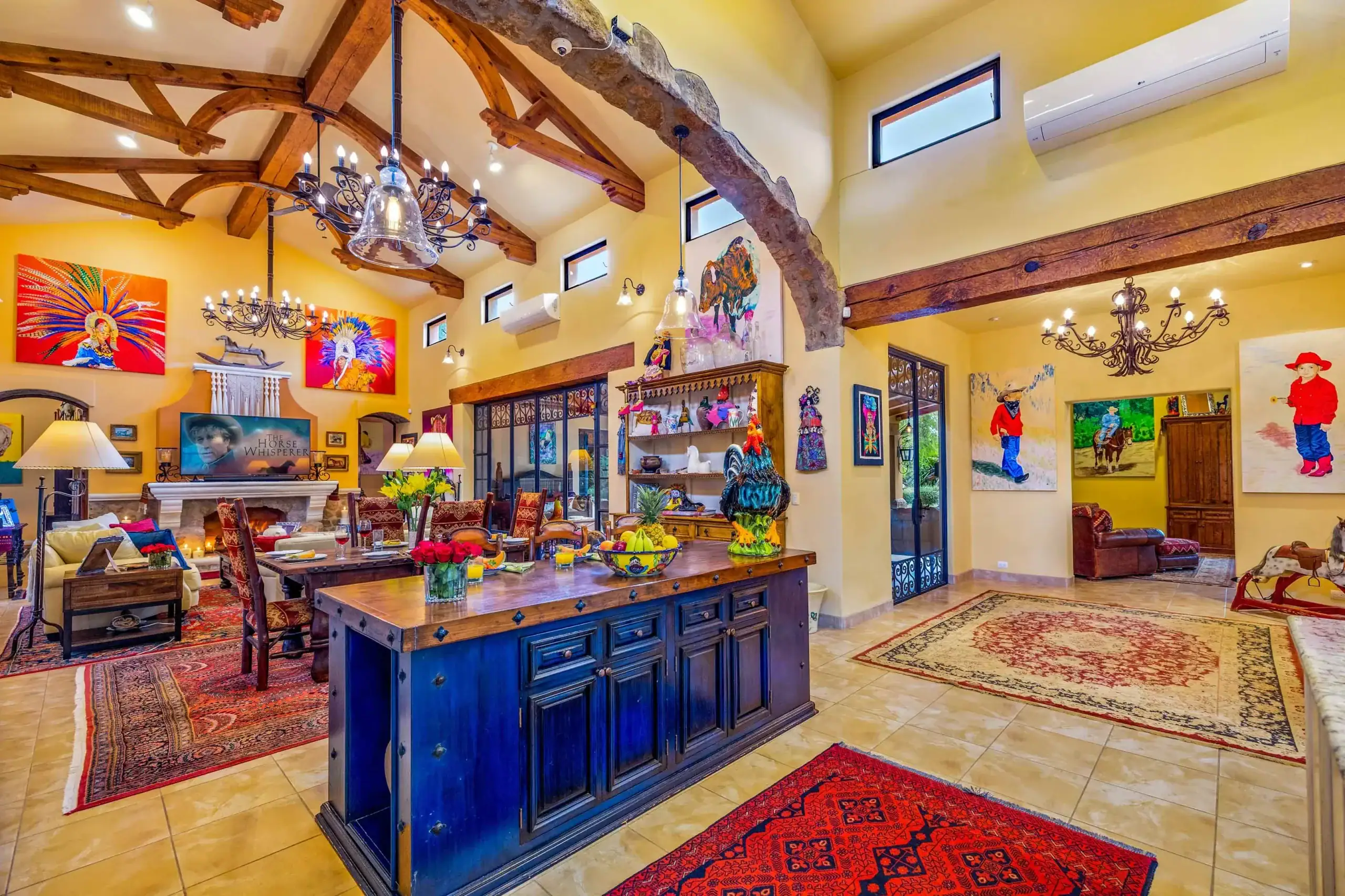 Bright living/dining room with yellow walls, exposed wooden beams, and a large dark wood island centerpiece, San Miguel de Allende