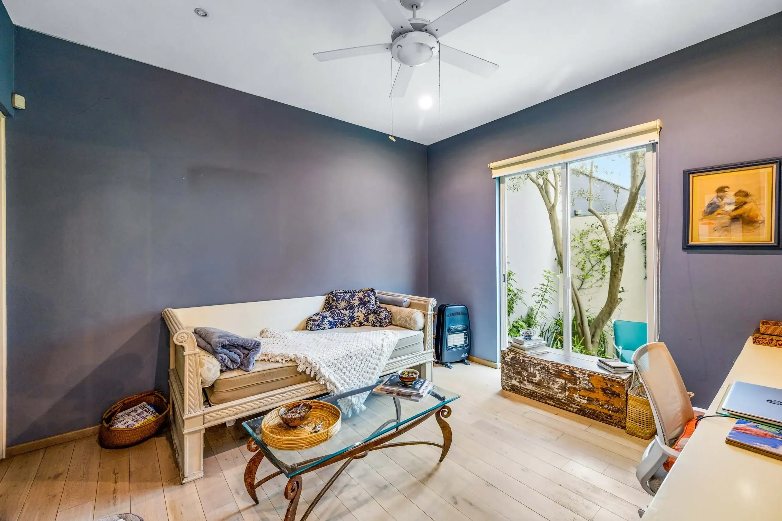 Living room with dark gray walls, a white ceiling fan, and a sliding door opening to a garden, San Miguel de Allende