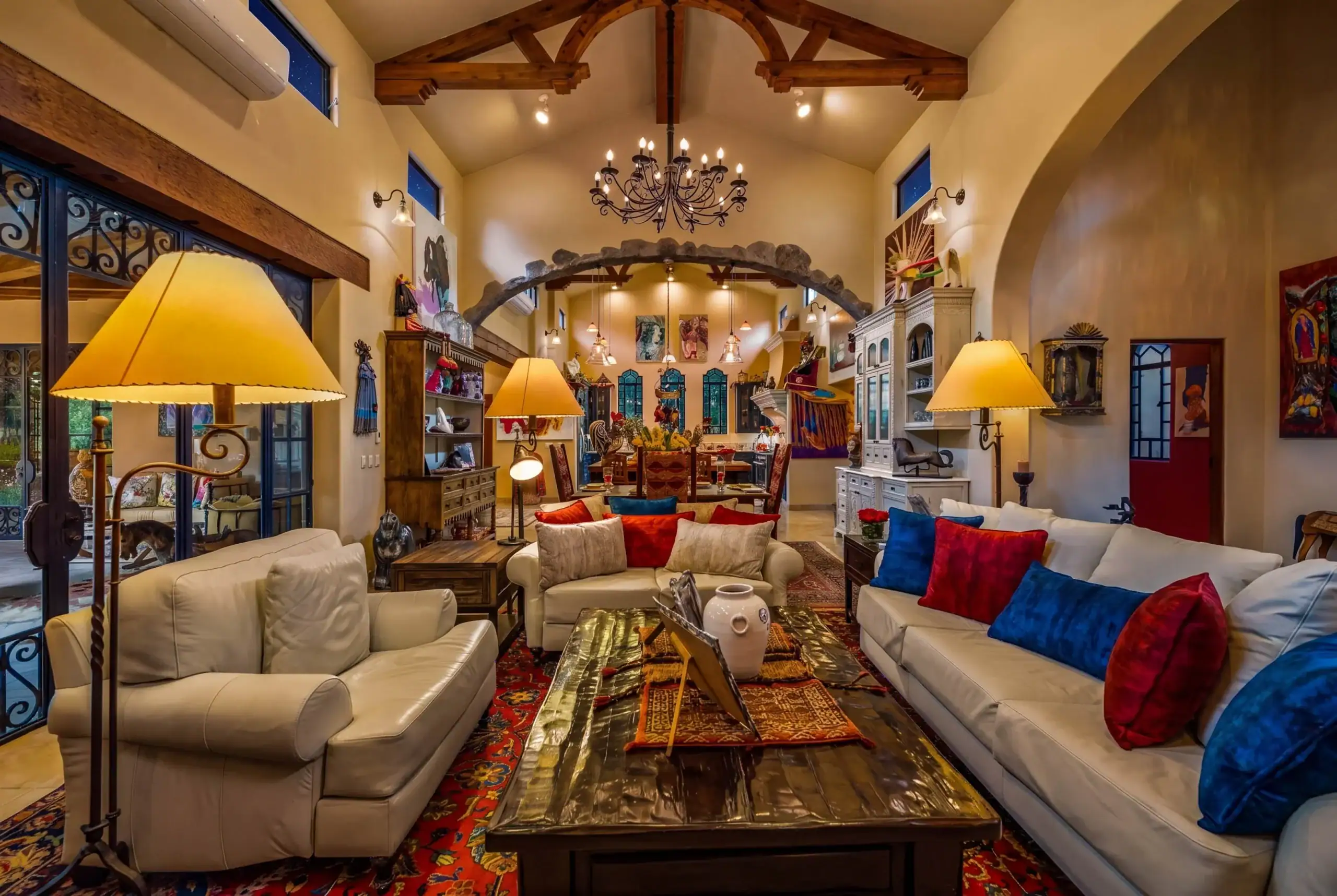 Cozy, eclectic living room with cream sofas, colorful cushions, wooden ceiling beams, and a long coffee table, San Miguel de Allende