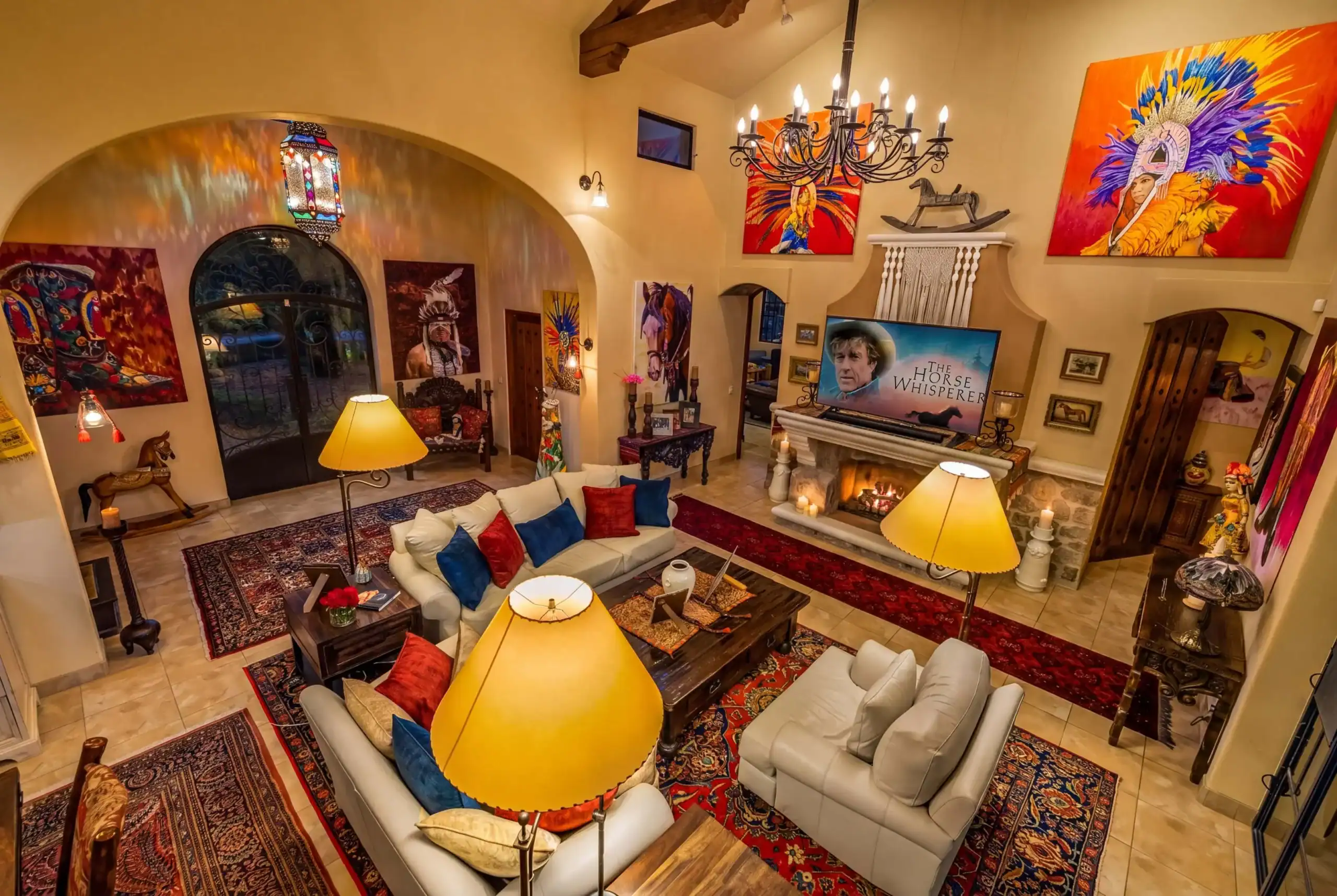 Cozy living room with cream sofas and red/blue cushions, warm lighting, and bold wall art on beige walls, San Miguel de Allende