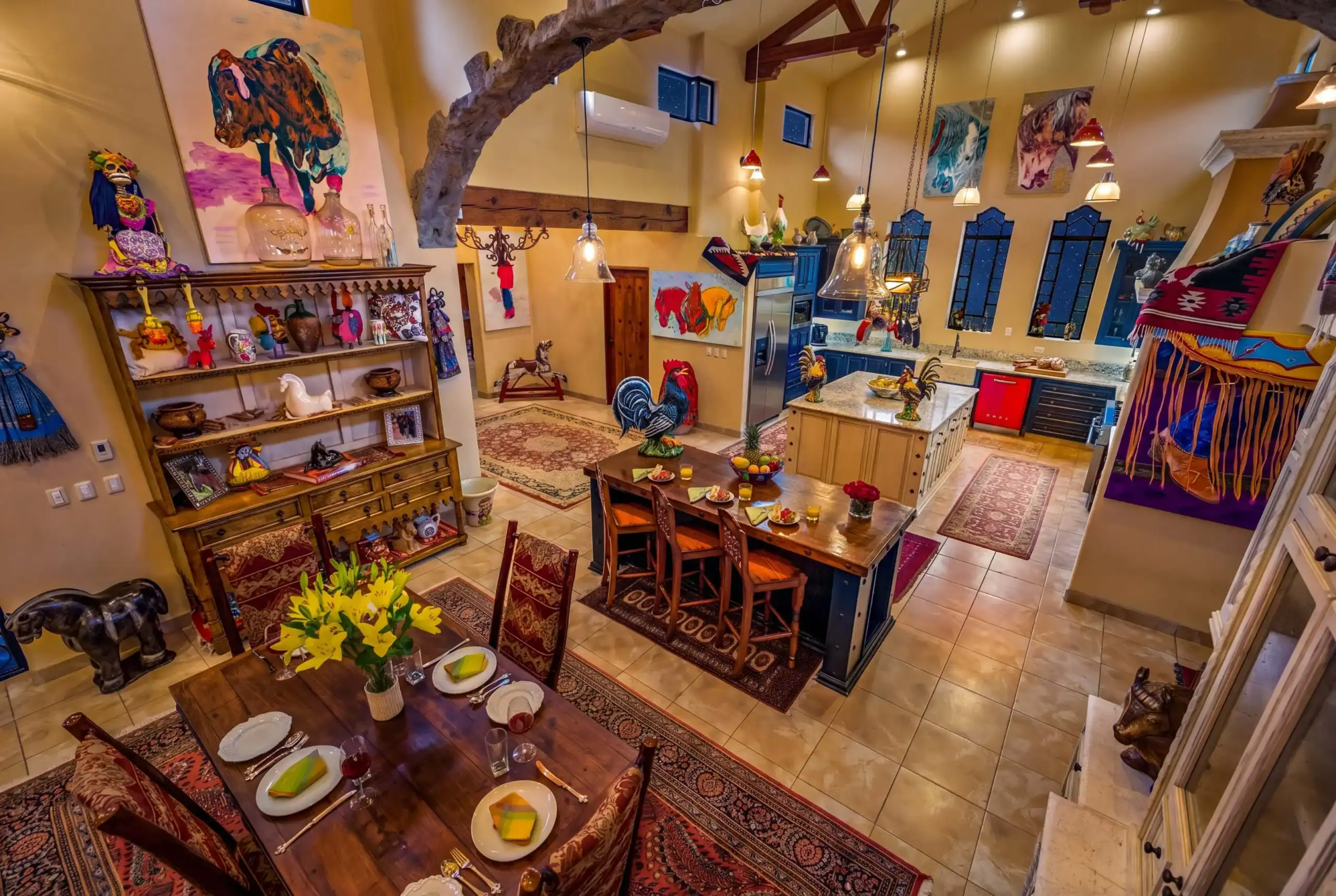 Colorful bohemian dining area with a wooden table set for a meal, shelves of pottery, and vibrant animal sculptures throughout the room, San Miguel de Allende