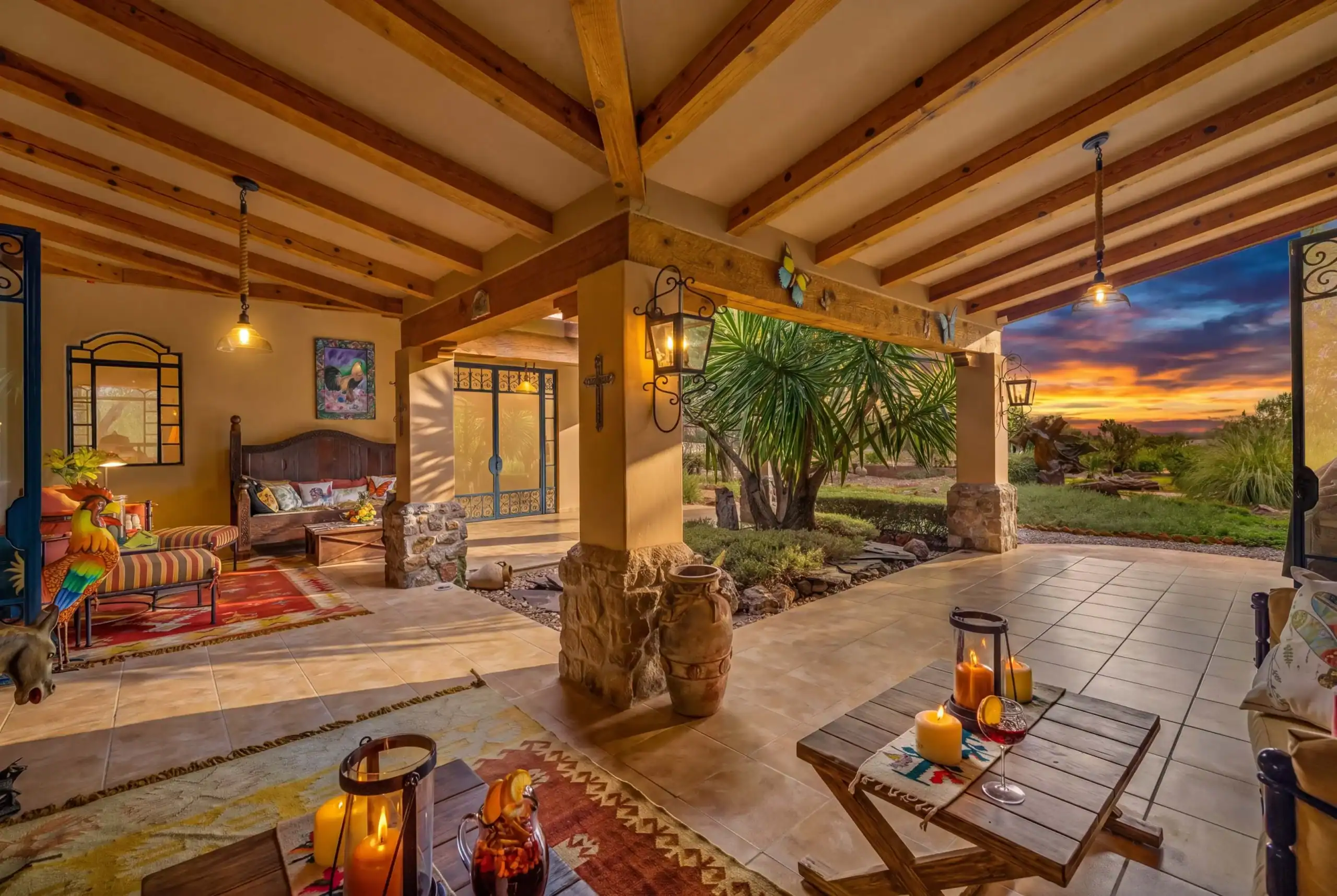 Sunset view of a covered patio with wooden beams, wicker seating, and warm candlelight, San Miguel de Allende
