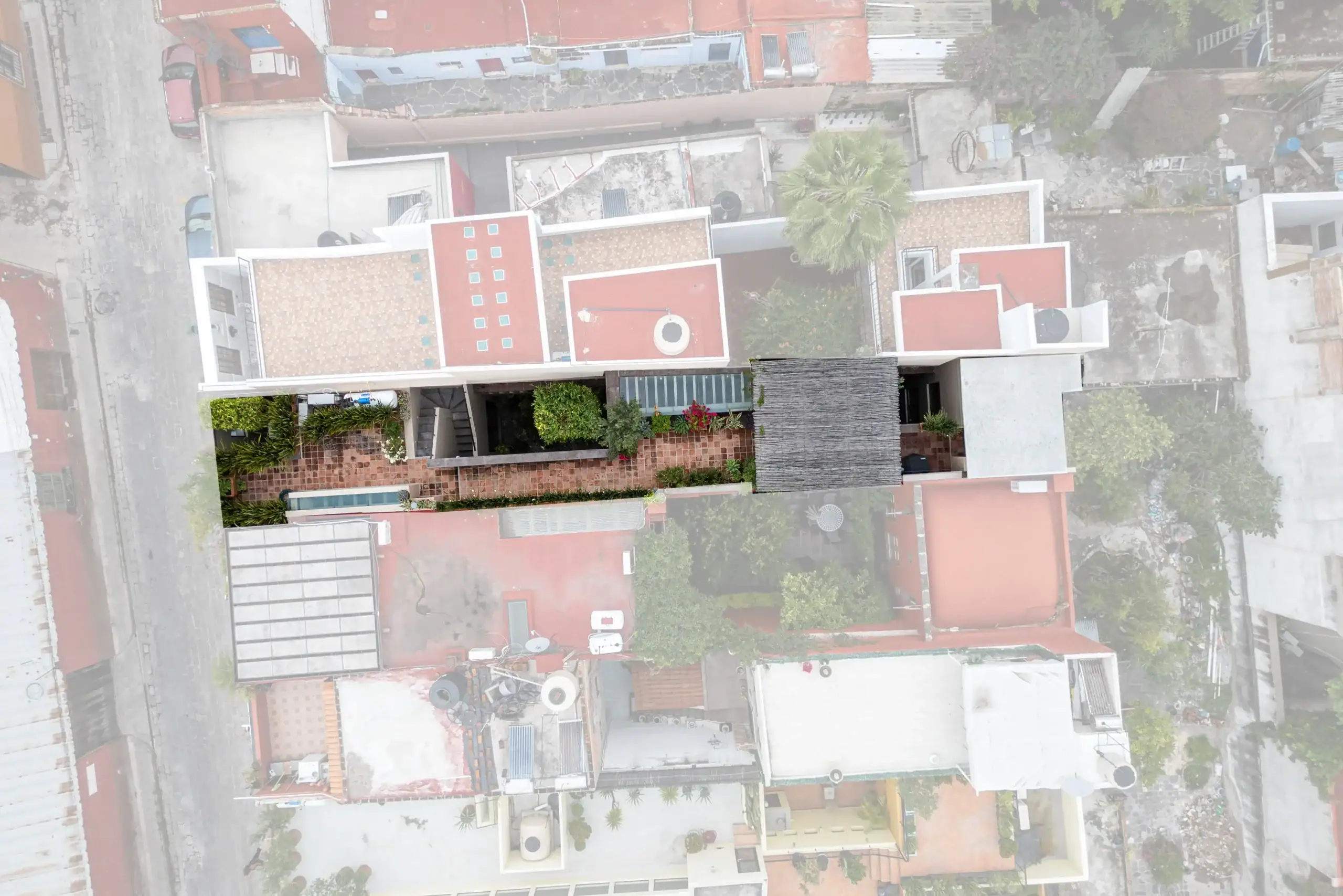 Aerial top-down view of a residential complex with red-tiled roofs, courtyards, and scattered greenery, San Miguel de Allende