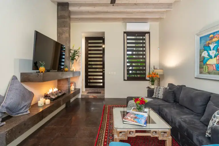 Cozy living room with a stone fireplace, candles, and a mounted TV on the mantel, San Miguel de Allende