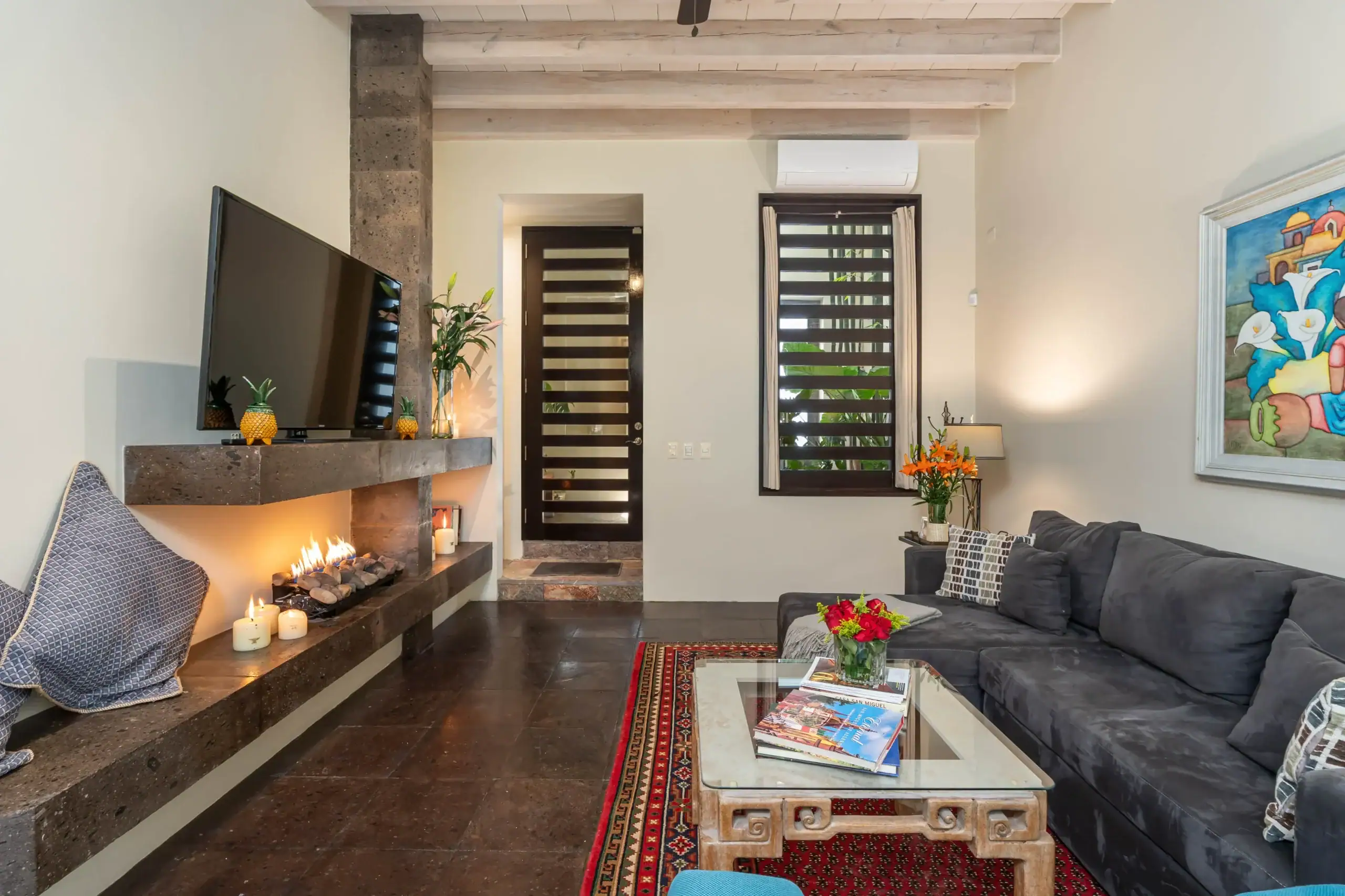 Cozy living room with a stone fireplace, candles, and a mounted TV on the mantel, San Miguel de Allende