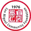 Circular badge/medal with a red heraldic shield at the center and a gray border with text around it.