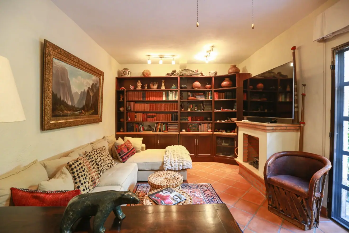 Casa Privada Baeza, den with a bookshelf wall, fireplace and a leather chair, San Miguel de Allende