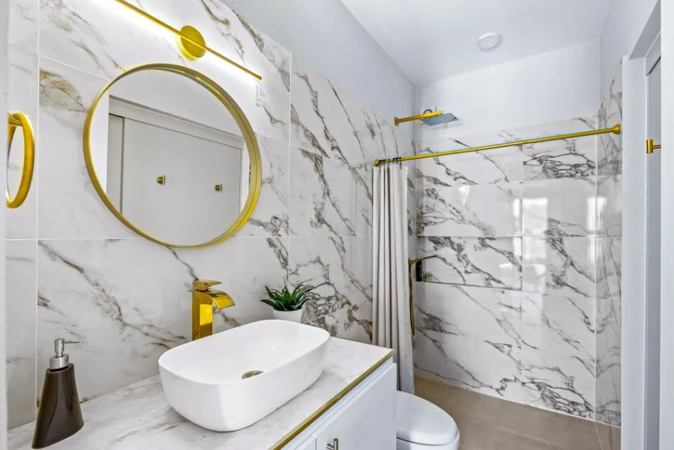 Casa Angel, bathroom with a white marble shower, round gold mirror and vessel sink, San Miguel de Allende