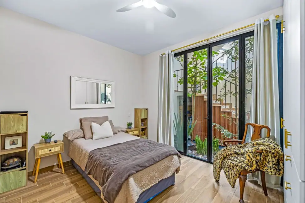 Casa Angel, bedroom with glass doors to a planted atrium and a leopard-print throw, San Miguel de Allende
