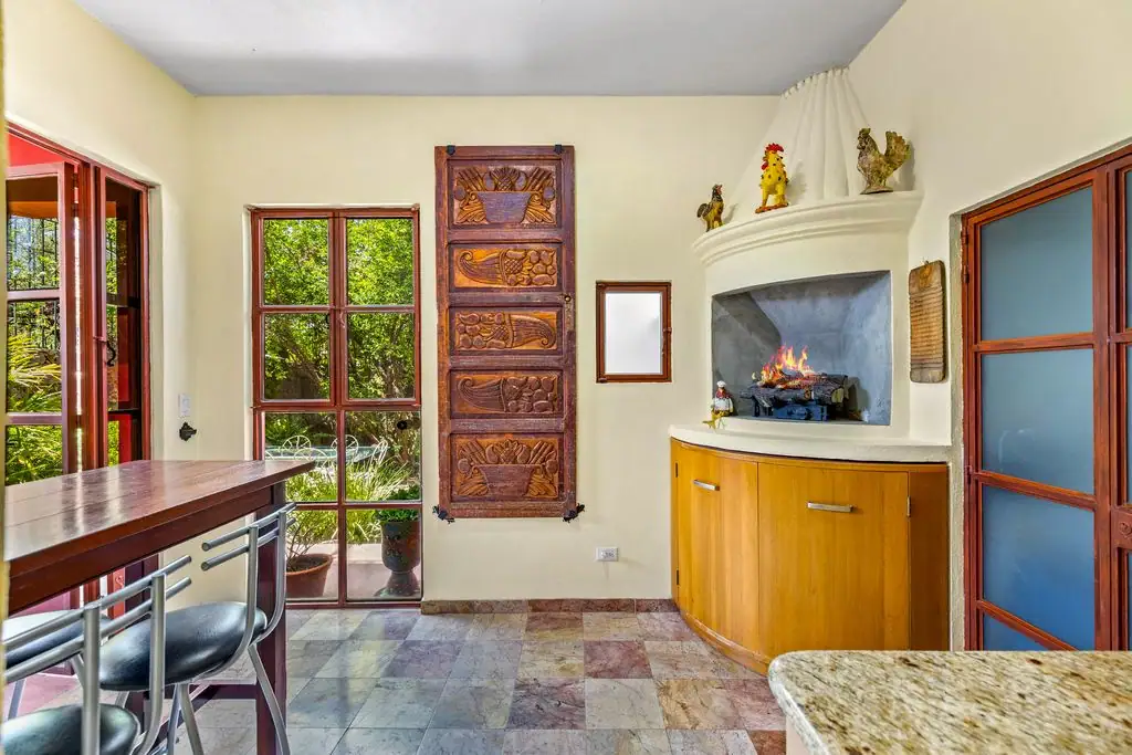 Cozy kitchen with a built‑in fireplace, curved wood cabinet, and glass doors opening to a garden, San Miguel de Allende