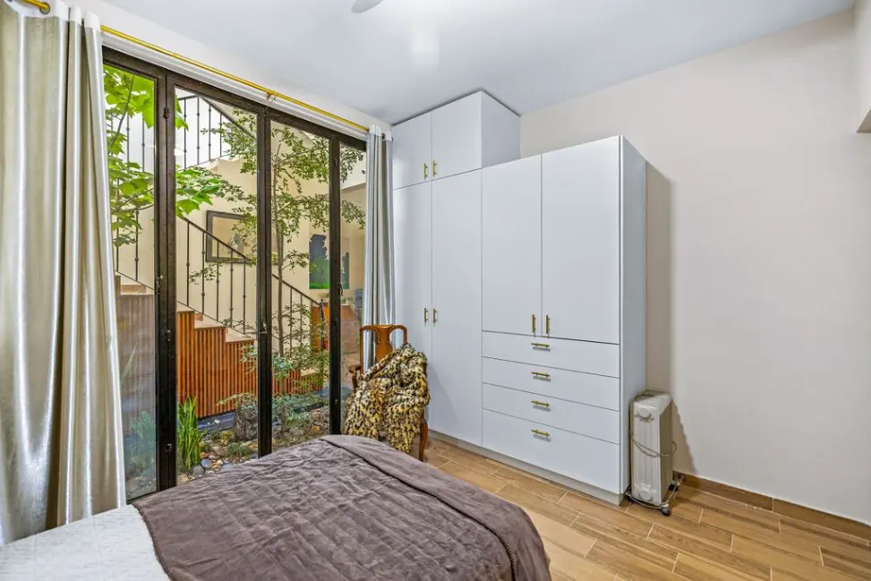 Casa Angel, bedroom corner with glass doors to the atrium and a white wardrobe, San Miguel de Allende