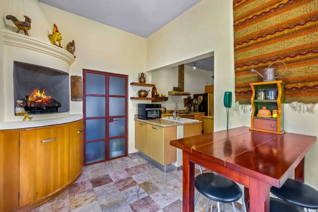 Cozy kitchen with a built-in fireplace, wooden cabinets, and a frosted glass door at the center-right, San Miguel de Allende