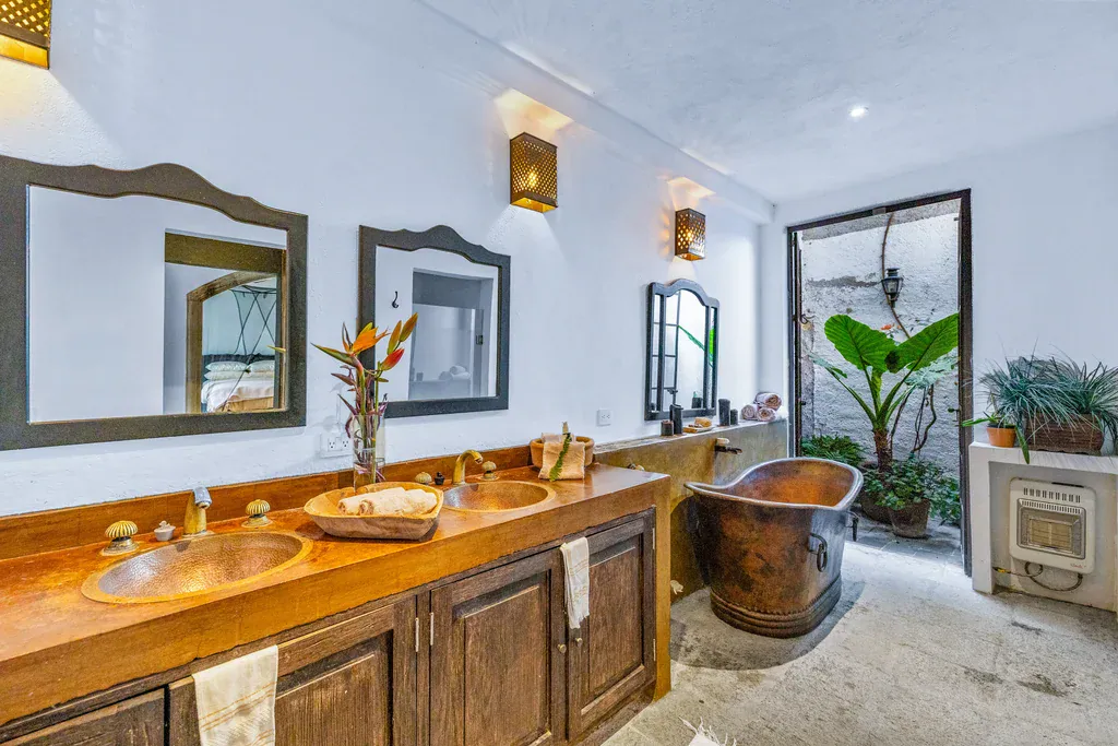 Casa Clae, bathroom with a copper soaking tub, double copper sinks and a carved wood vanity, San Miguel de Allende