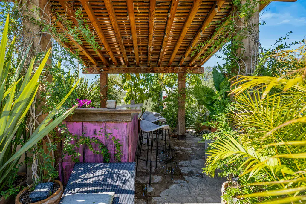 Casa Clae, pergola-covered outdoor bar with stools among plants, San Miguel de Allende