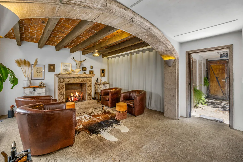 Casa Clae, living room with a stone fireplace, leather armchairs and a cowhide rug, San Miguel de Allende