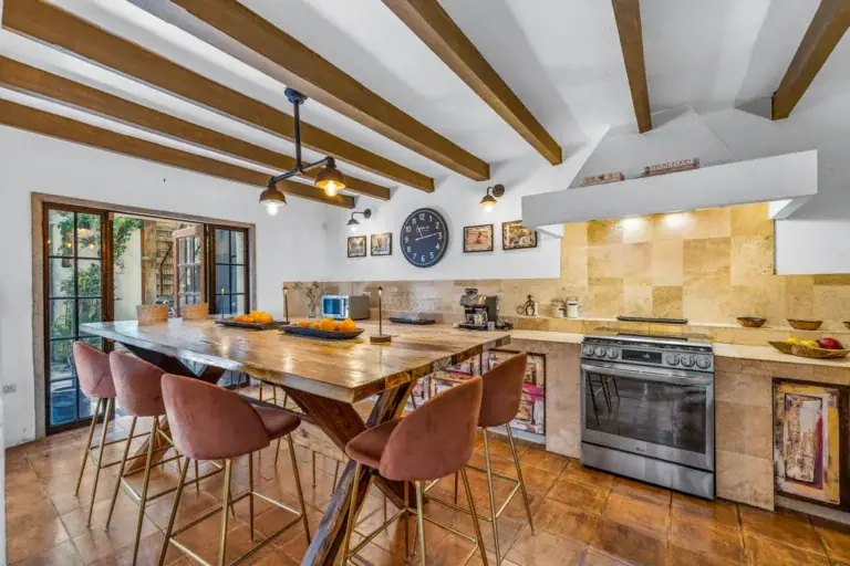 Casa Clae, kitchen with a wood table, bar stools and a stainless steel range, San Miguel de Allende