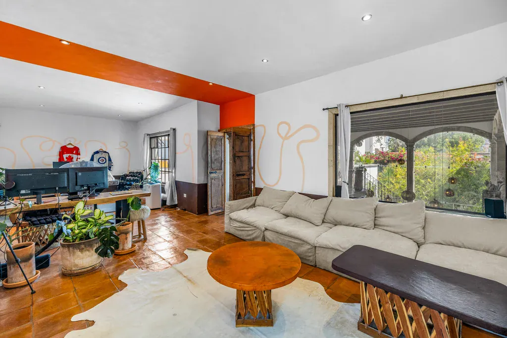 Casa Clae, office and family room with a white sectional and an orange accent wall, San Miguel de Allende