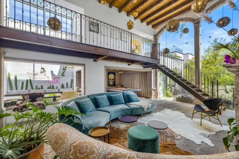 Casa Clae, great room with a double-height ceiling, a teal sectional sofa and a mezzanine, San Miguel de Allende