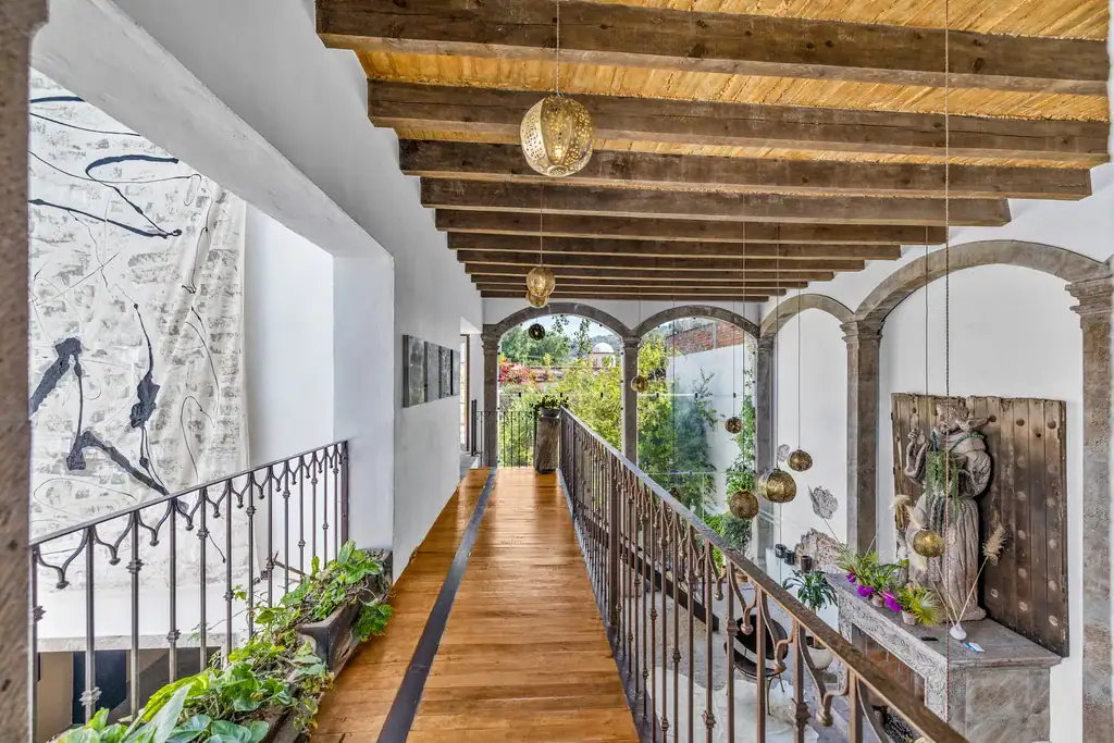 Casa Clae, upper gallery with a wood-beamed ceiling and an iron railing overlooking the garden, San Miguel de Allende