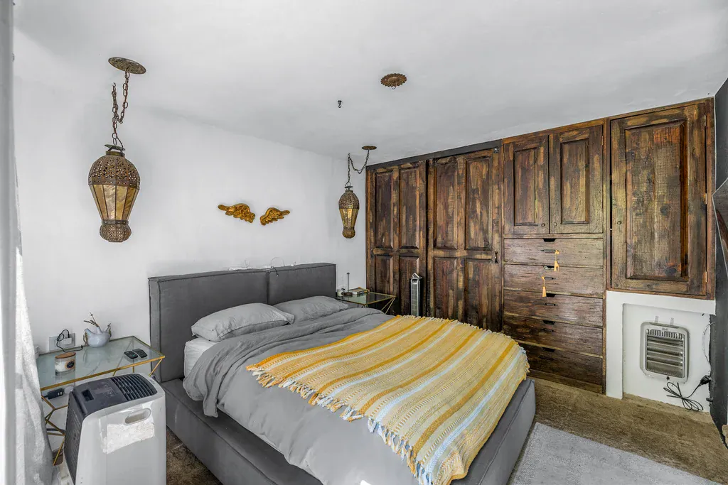 Casa Clae, bedroom with built-in rustic wood wardrobes and a gray upholstered bed, San Miguel de Allende