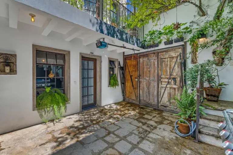 Casa Clae, courtyard with a rustic wooden barn door and potted ferns, San Miguel de Allende