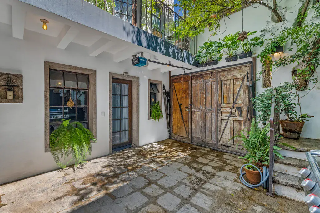 Casa Clae, courtyard with a rustic wooden barn door and potted ferns, San Miguel de Allende