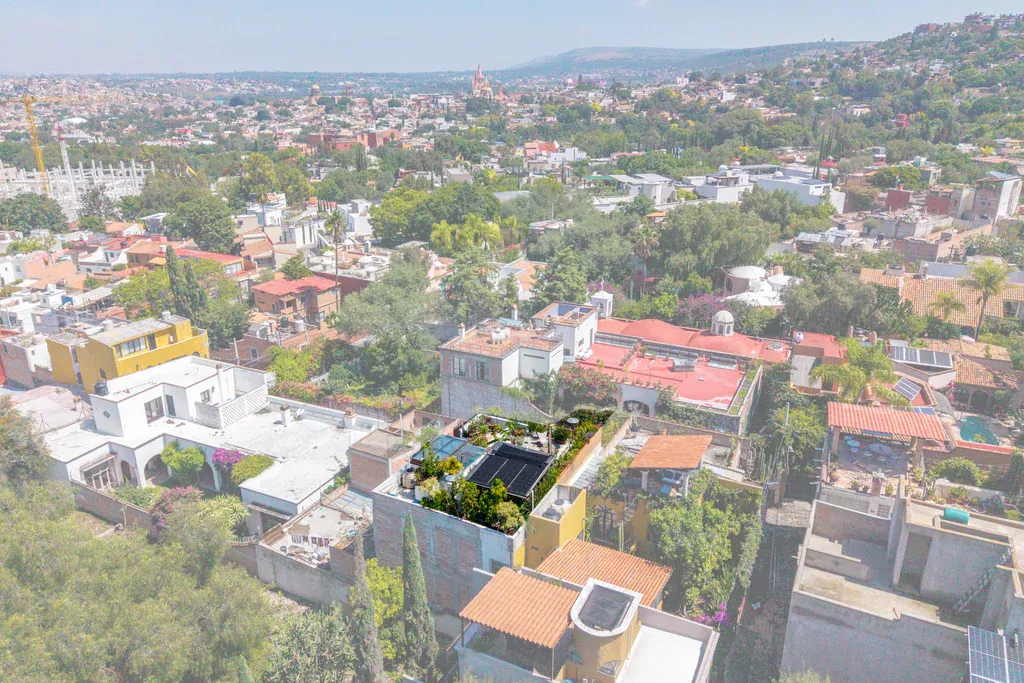 Casa Clae, aerial view of the house among neighboring rooftops, with the city beyond, San Miguel de Allende