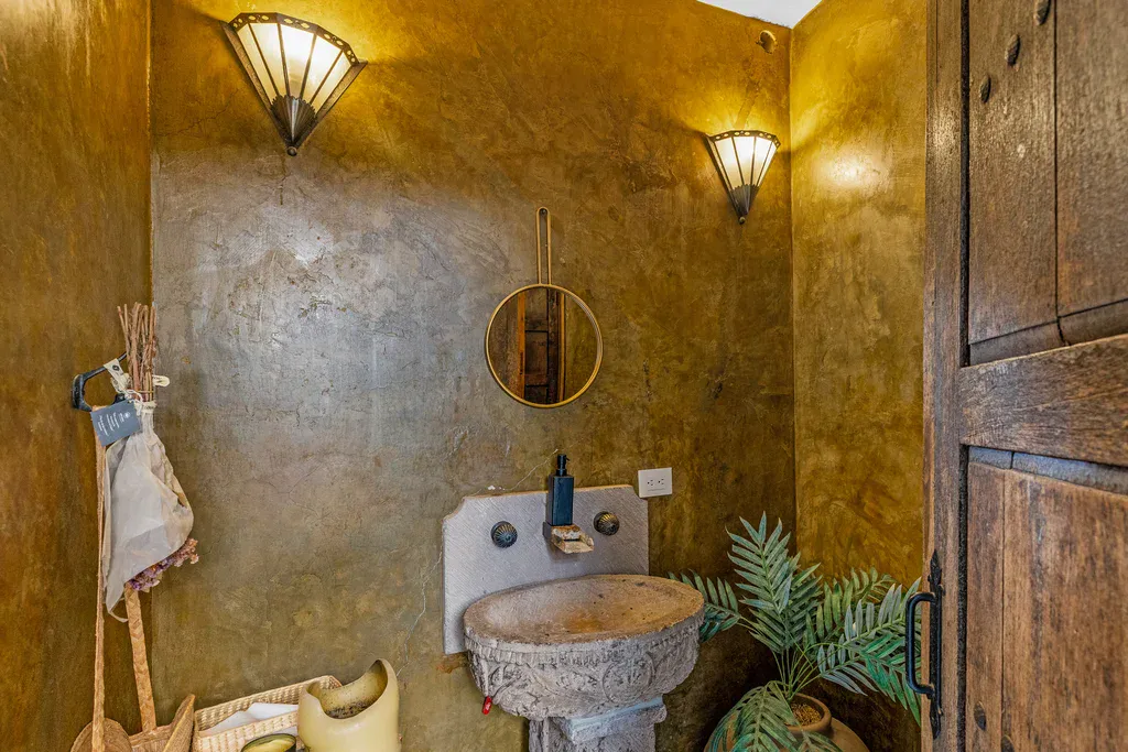 Casa Clae, powder room with a gold plaster wall and a stone pedestal sink, San Miguel de Allende