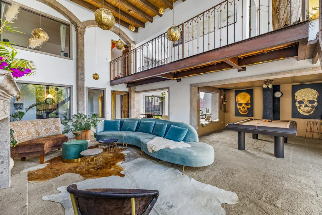 Casa Clae, great room with a mezzanine, a billiard table and a teal curved sofa, San Miguel de Allende
